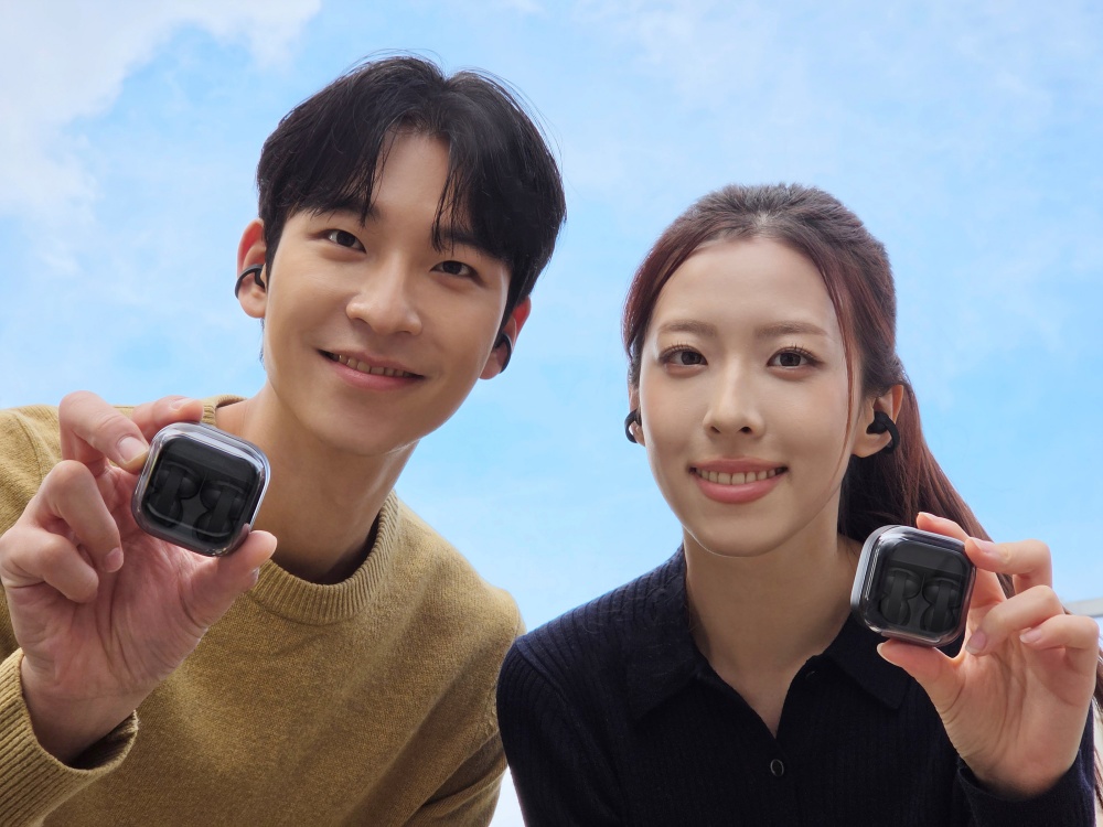 Двоє людей демонструють чорні навушники-кліпси Samsung Galaxy Buds On у зарядних футлярах